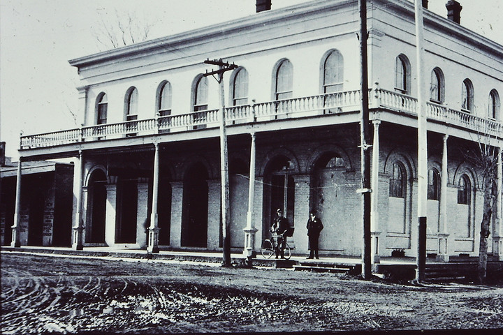 This photo shows the Bidwell Store at a time when there was a second story and balcony and porch surrounding the building. Compare the windows shown in the photo with those still on the north side of the building.